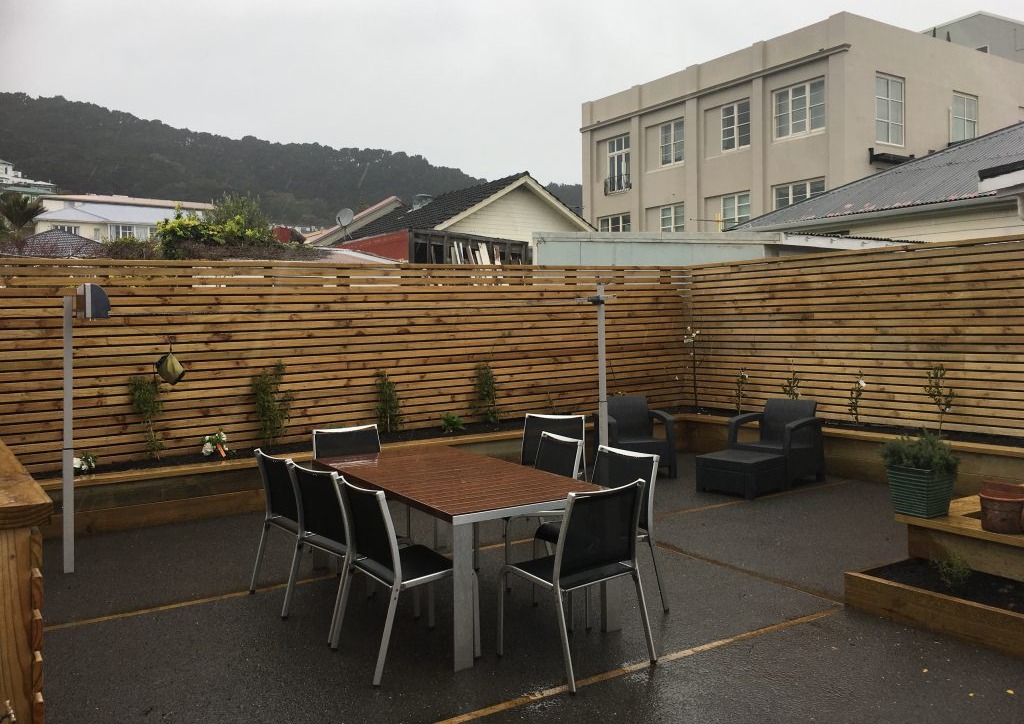 Completed courtyard with an outdoor dining setting beside a timber slat screen